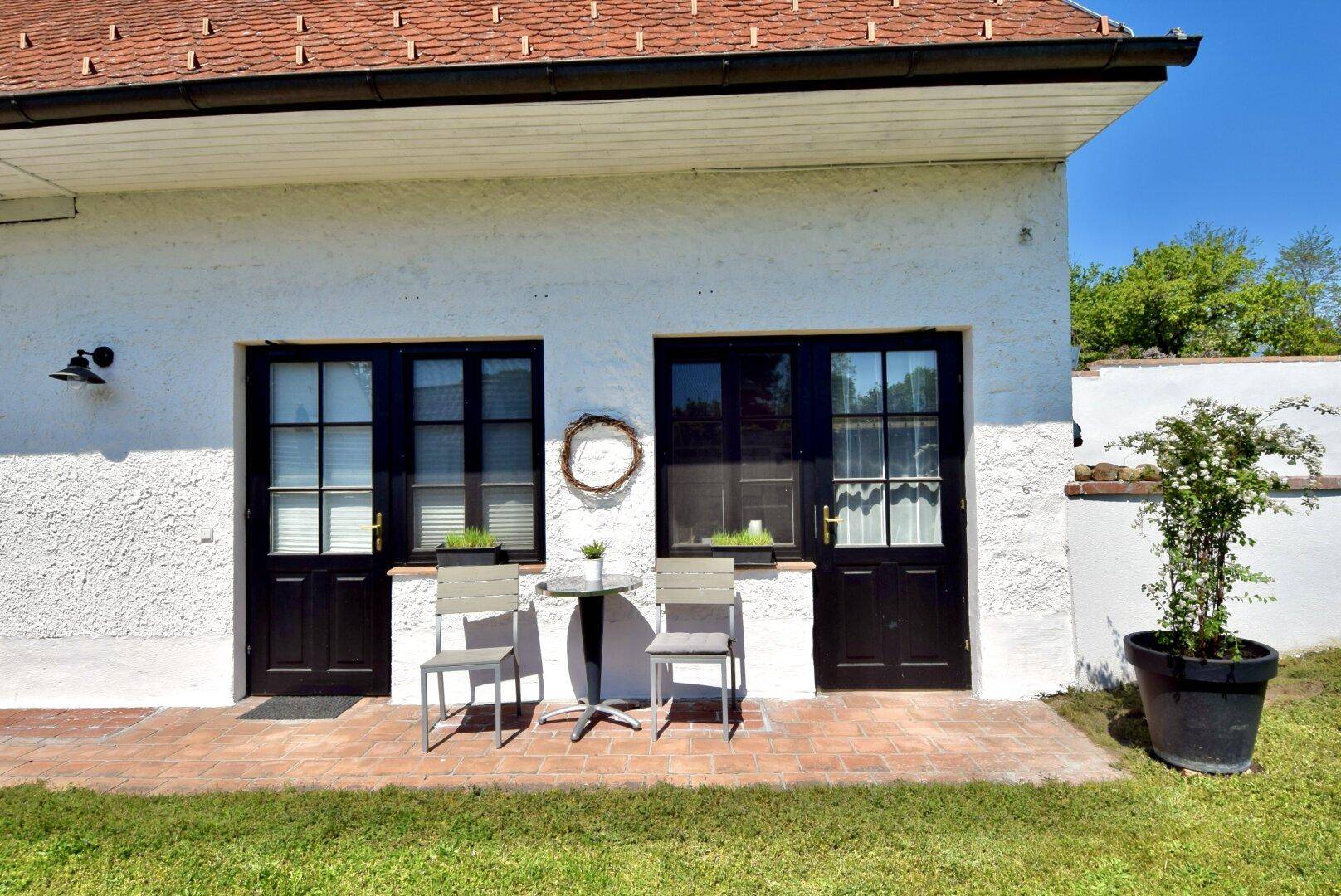 Kleiner gepflasterter Bereich vor dem Haus mit zwei Stühlen und einem Tisch für entspannte Momente.