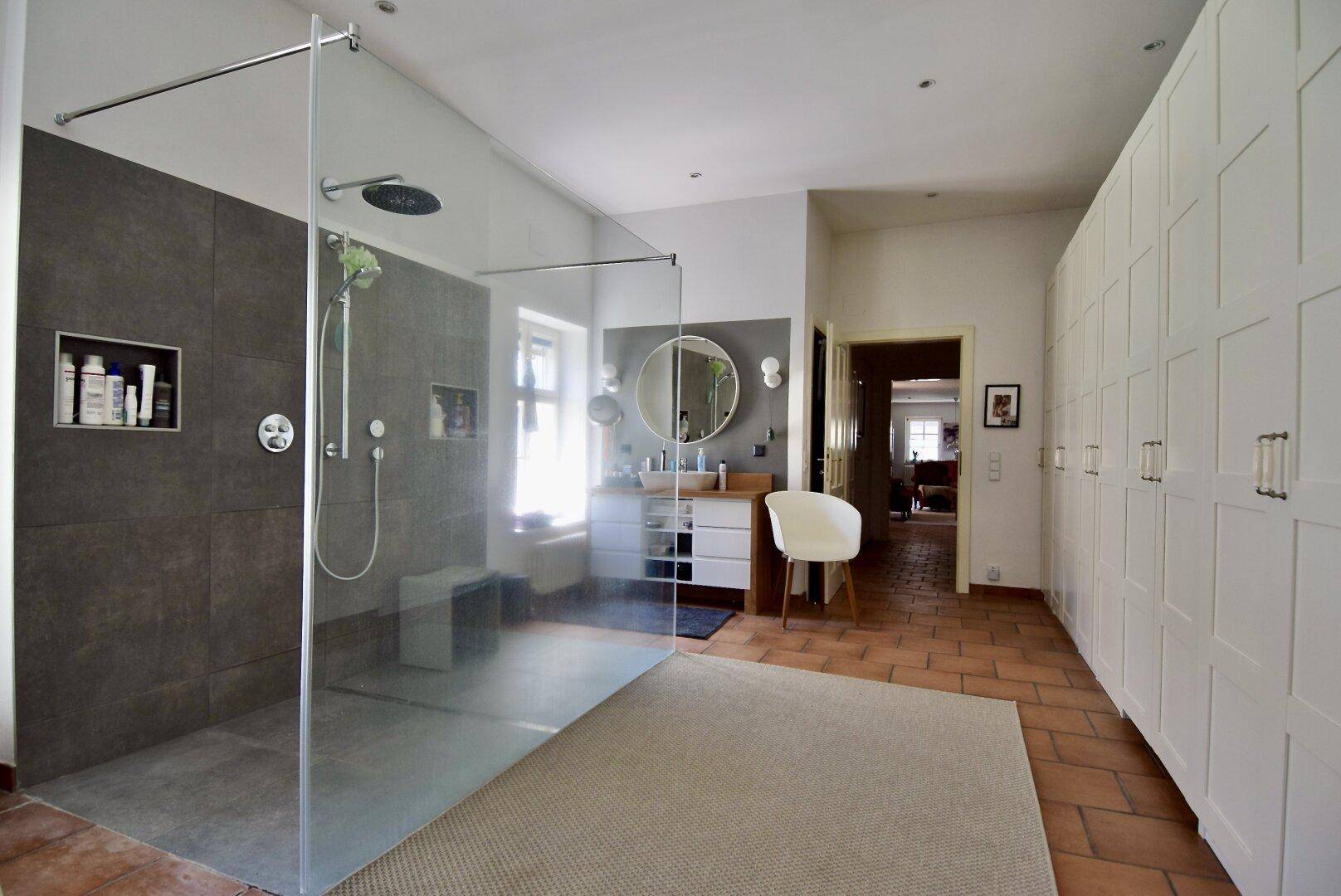 Geräumiges Badezimmer mit großer begehbarer Dusche, Doppelwaschbecken und viel Stauraum.