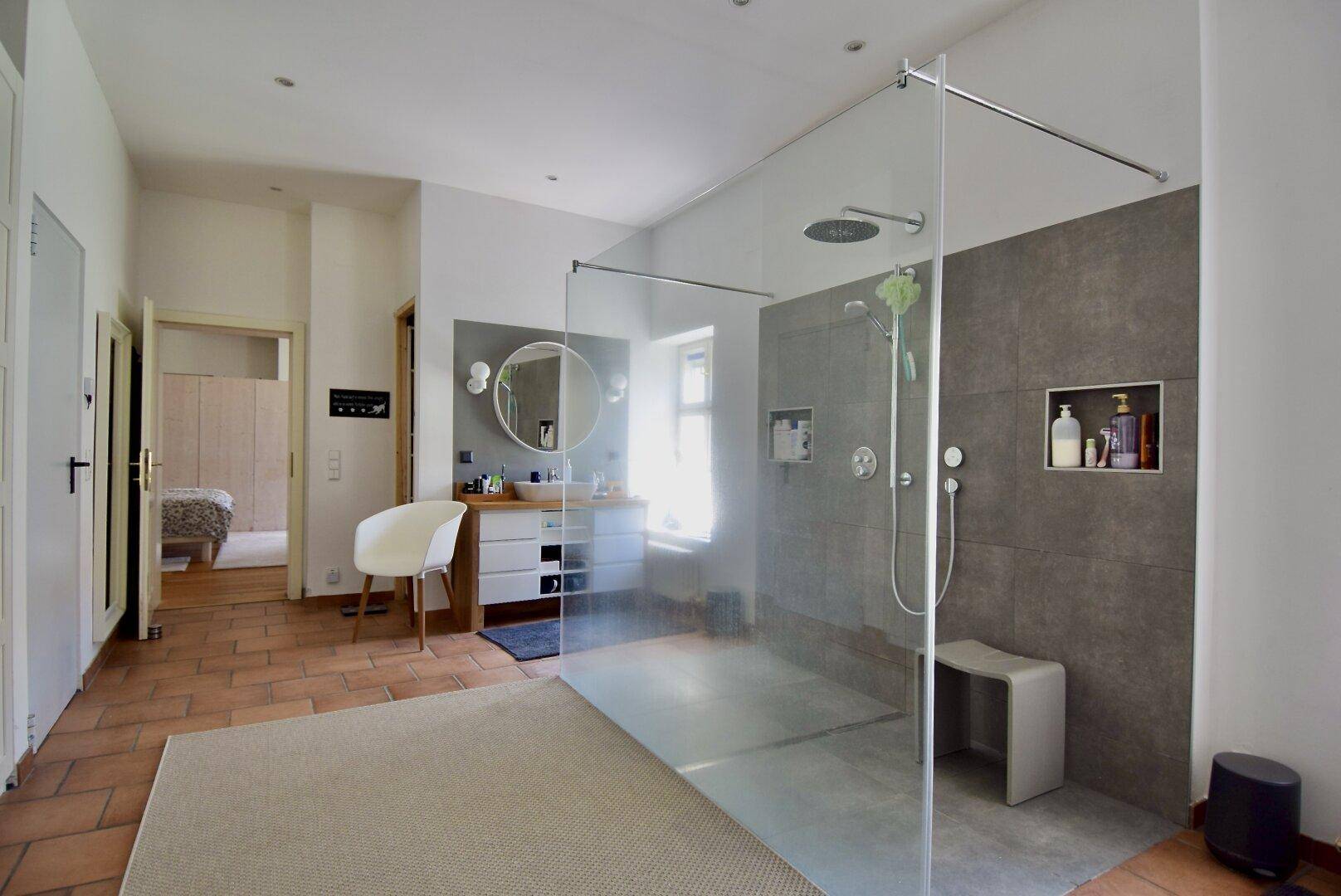 Modernes Badezimmer mit begehbarer Dusche, stilvollem Waschtisch und großem Spiegel, der den Raum erweitert.