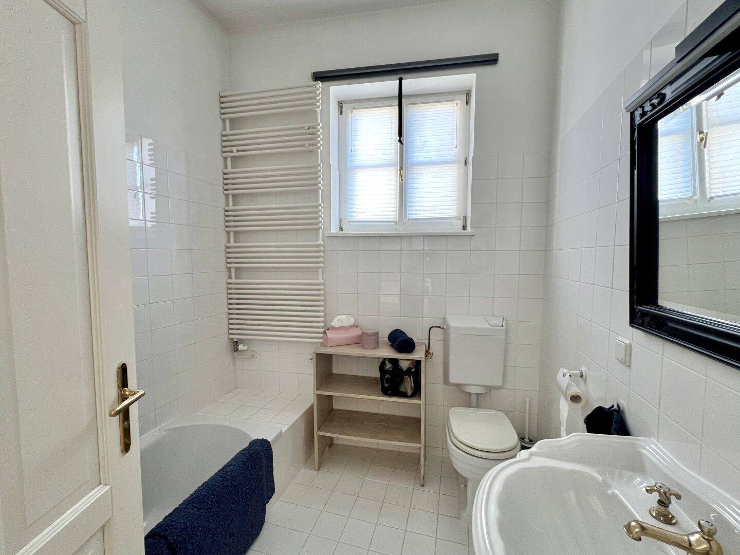 Klassisches Badezimmer mit Badewanne, WC, Waschbecken und beheiztem Handtuchhalter.
