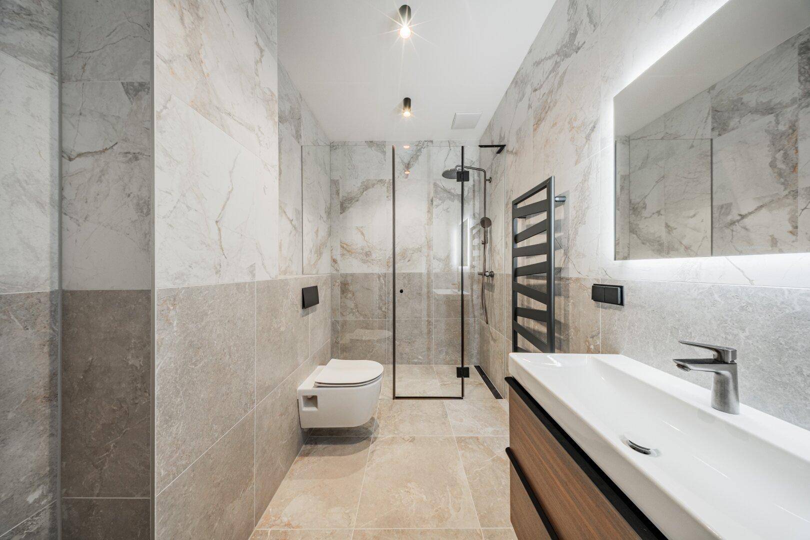 Modernes Badezimmer mit begehbarer Dusche, eleganten Marmorfliesen und beheiztem Handtuchhalter.