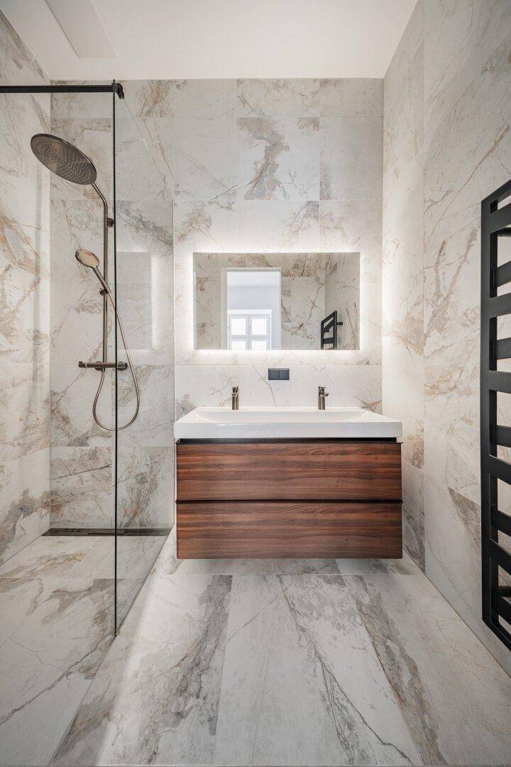 Elegantes Badezimmer mit Doppelwaschbecken, begehbarer Dusche und luxuriösen Marmorfliesen.