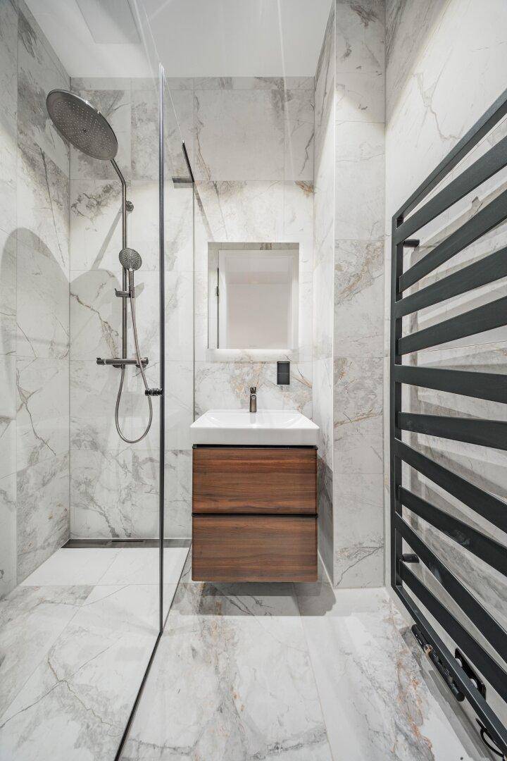 Modernes Badezimmer mit begehbarer Dusche, Einzelwaschbecken und Marmorfliesen.