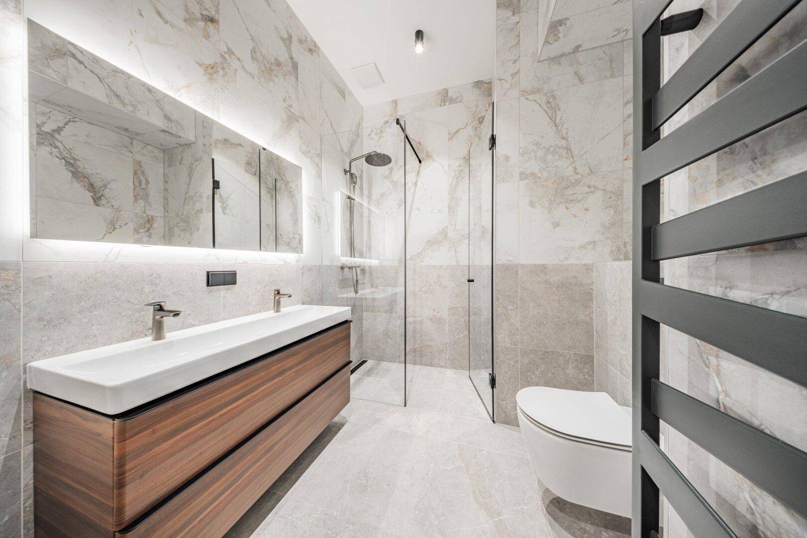 Elegantes, modernes Badezimmer mit Doppelwaschbecken, begehbarer Dusche und Marmorfliesen.