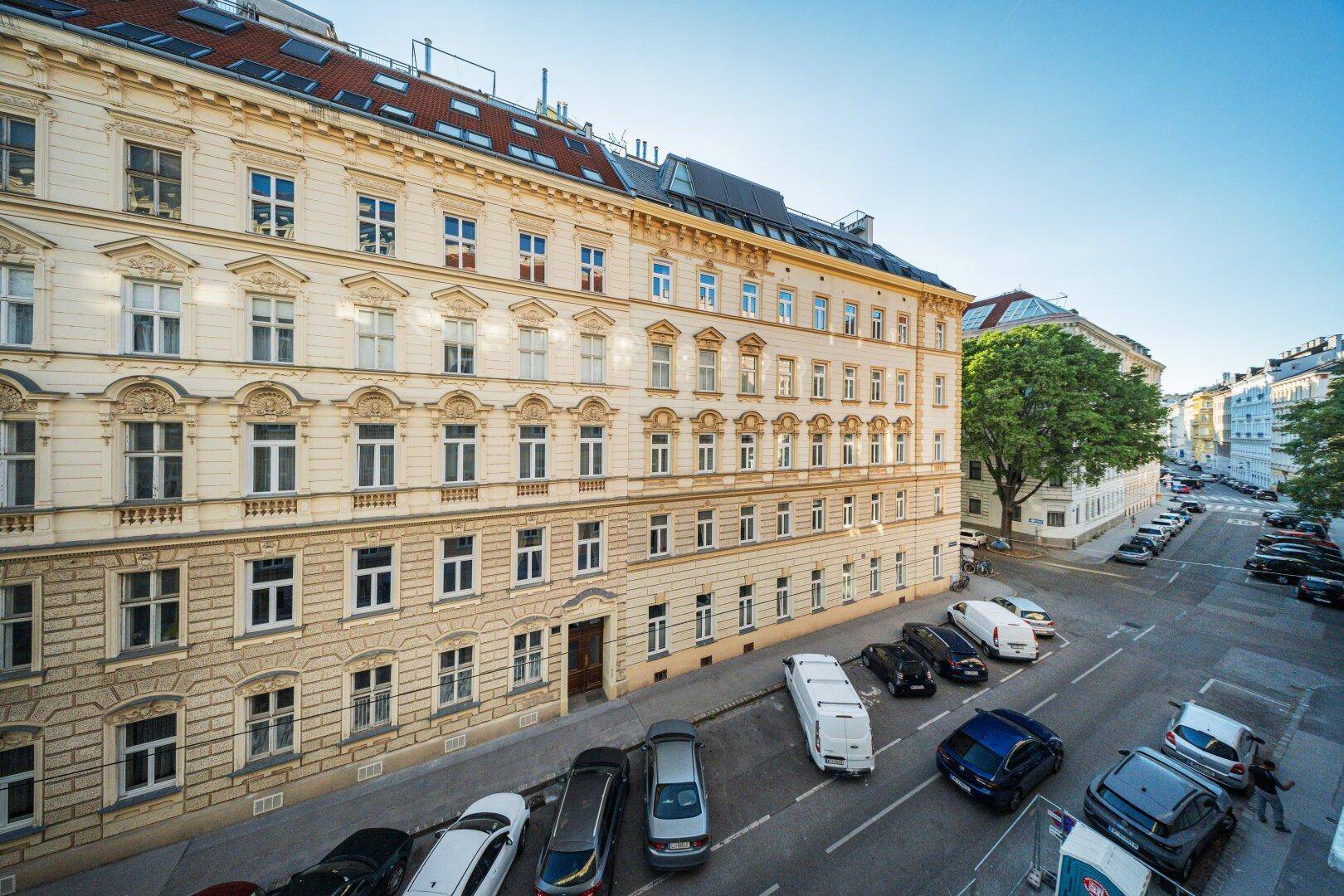 Panoramablick von einem Balkon über die historische Stadtstraße mit parkenden Autos.