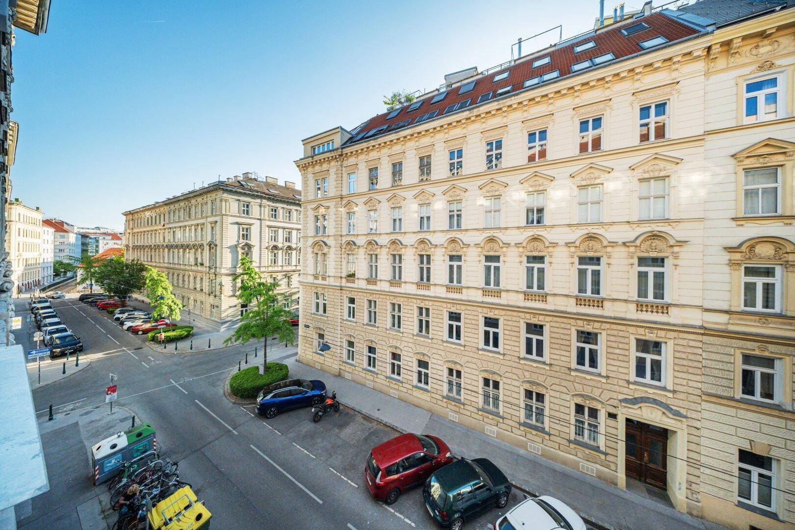 Weitläufiger Blick von einem Balkon auf die belebte Stadtstraße und umliegende Gebäude.