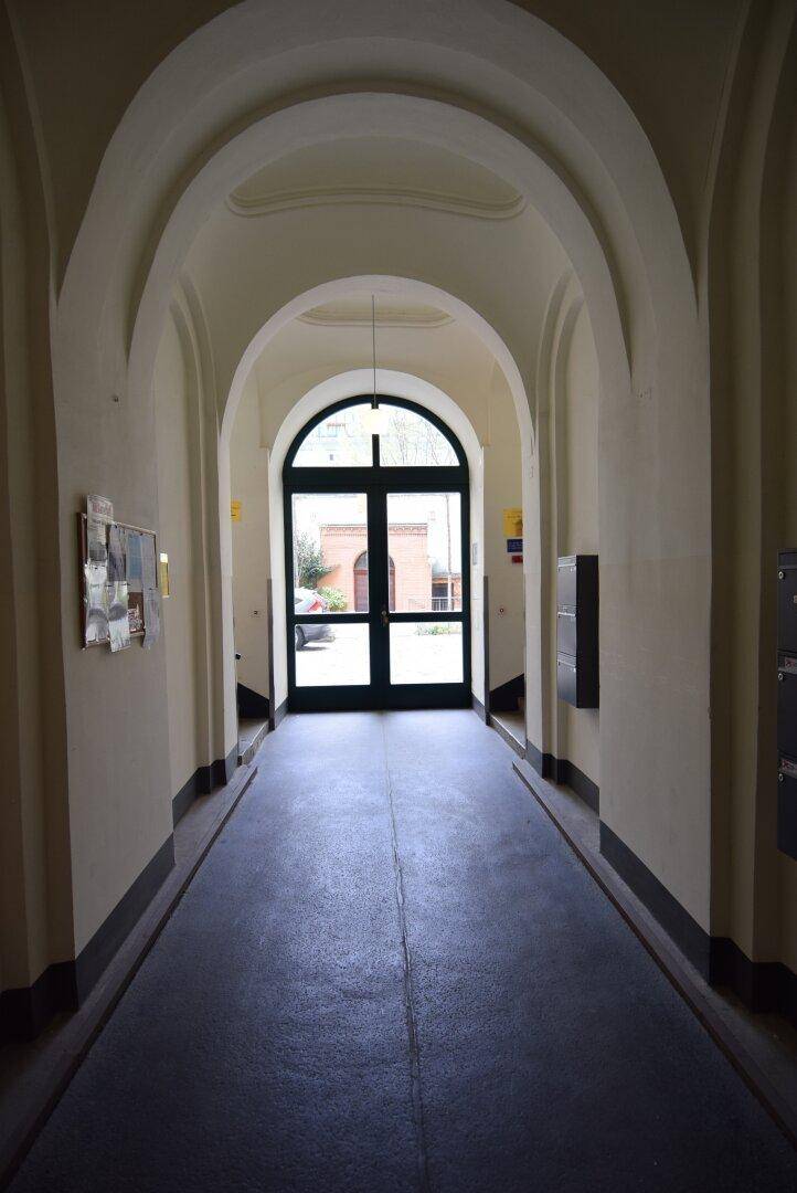 Eingangsbereich mit gewölbter Decke und großer, bogenförmiger Glastür, die nach draußen führt.