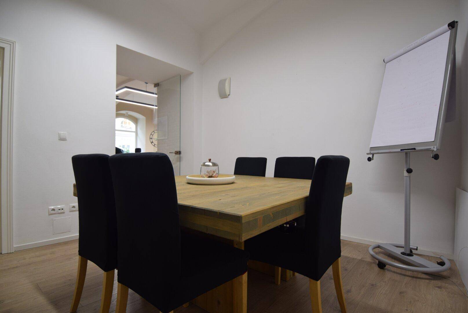 Besprechungsraum mit großem Holztisch, schwarzen Stühlen und Whiteboard, ideal für produktive Team-Meetings.