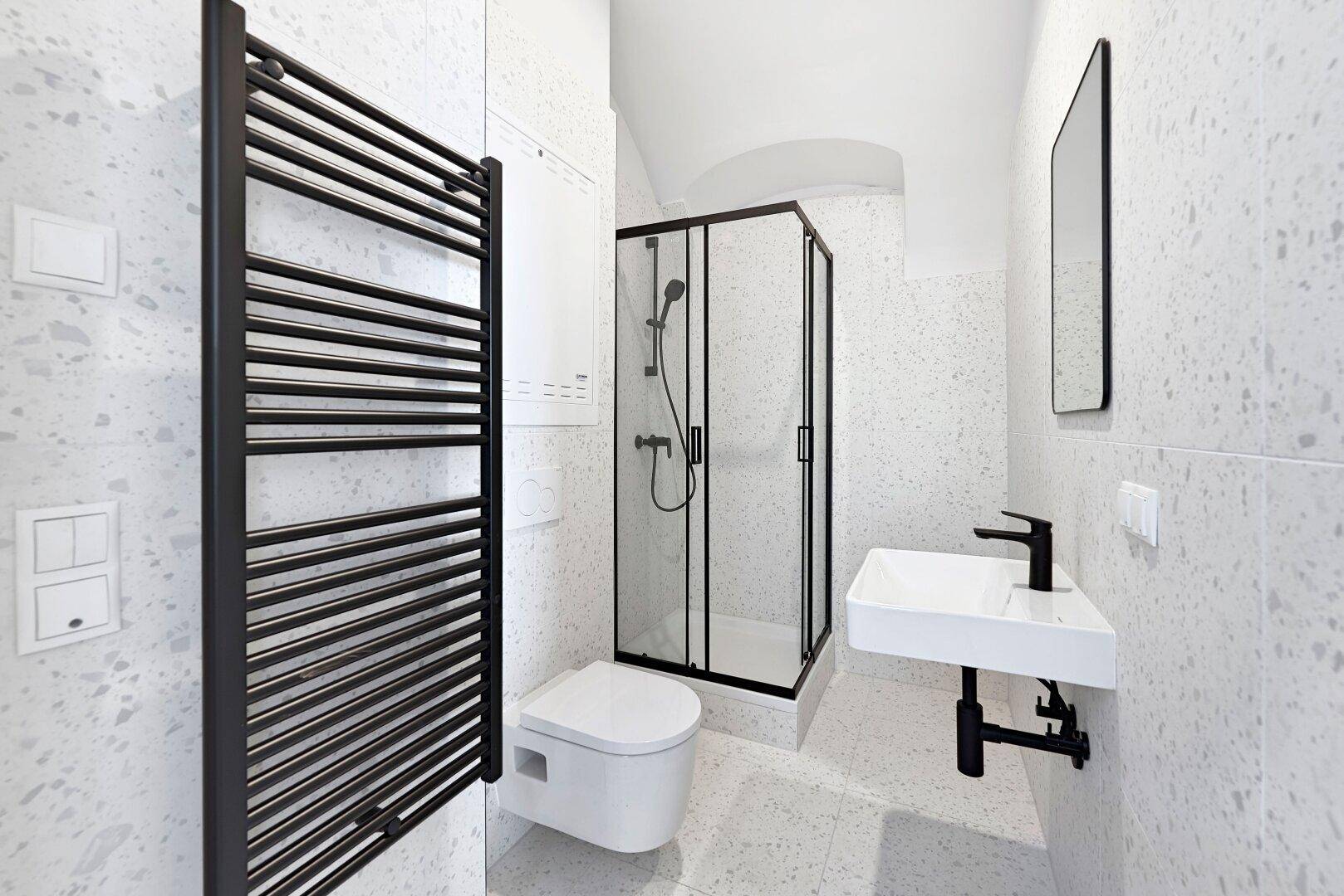 Modernes Badezimmer mit schwarzen Armaturen, Duschkabine und beheiztem Handtuchhalter.