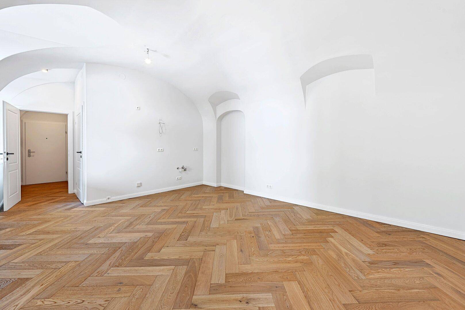 Geräumiges Zimmer mit elegantem Fischgrätparkett und charakteristischen Gewölbedecken.