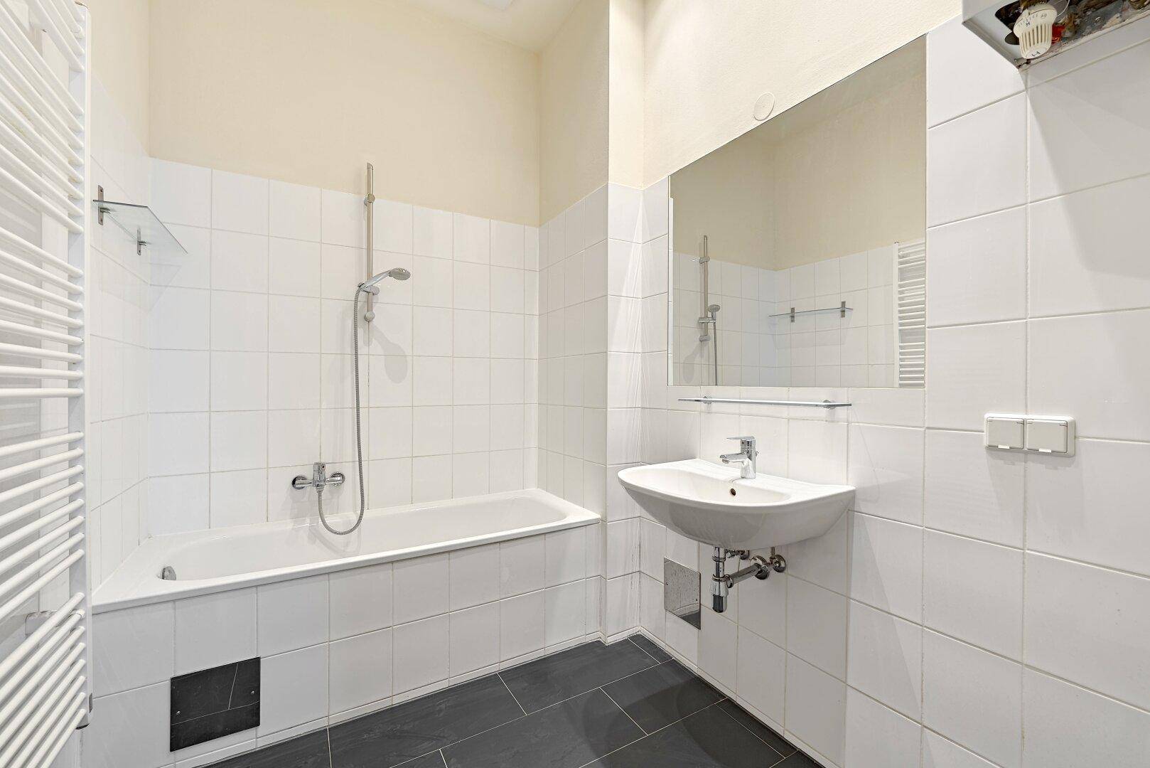 Modernes Badezimmer mit Badewanne, Duschfunktion, Waschbecken und weiß gefliesten Wänden.