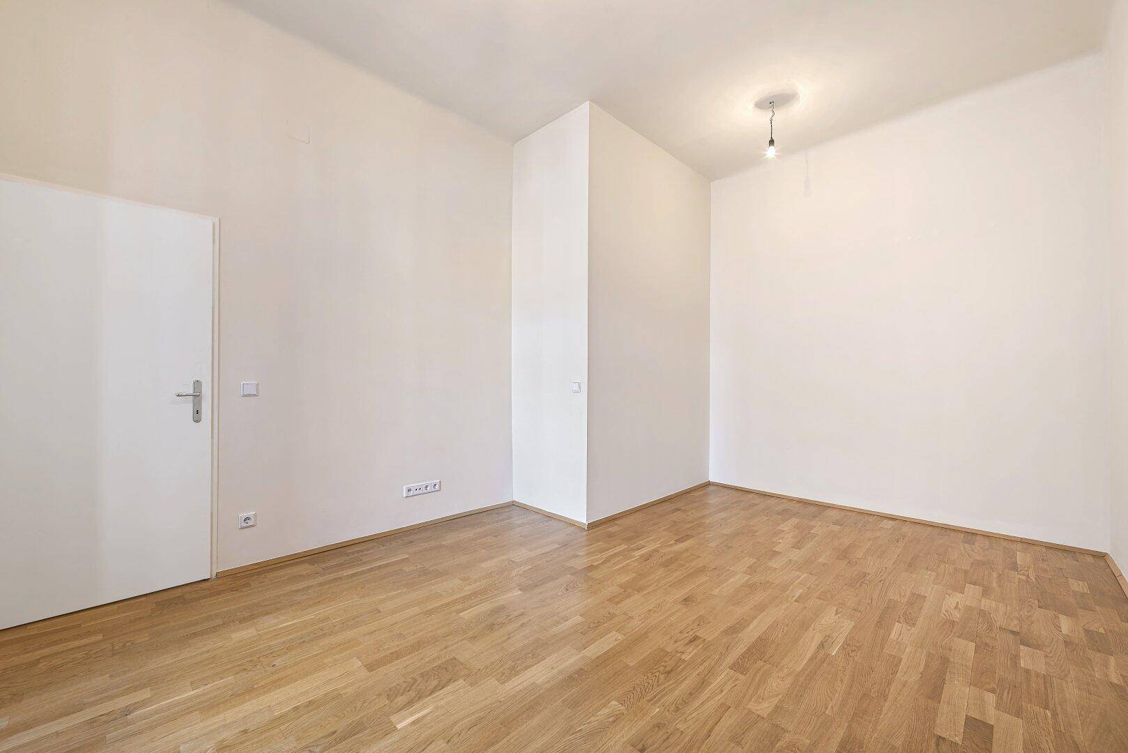 Ruhiges Zimmer mit Parkettboden und weißer Tür, ideal als Schlaf- oder Arbeitszimmer.