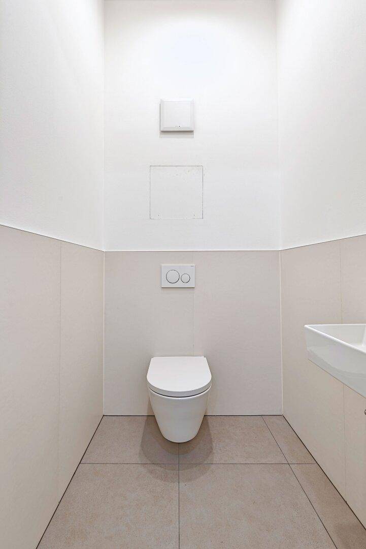 Modernes Gäste-WC mit wandhängender Toilette und minimalistischem Design.