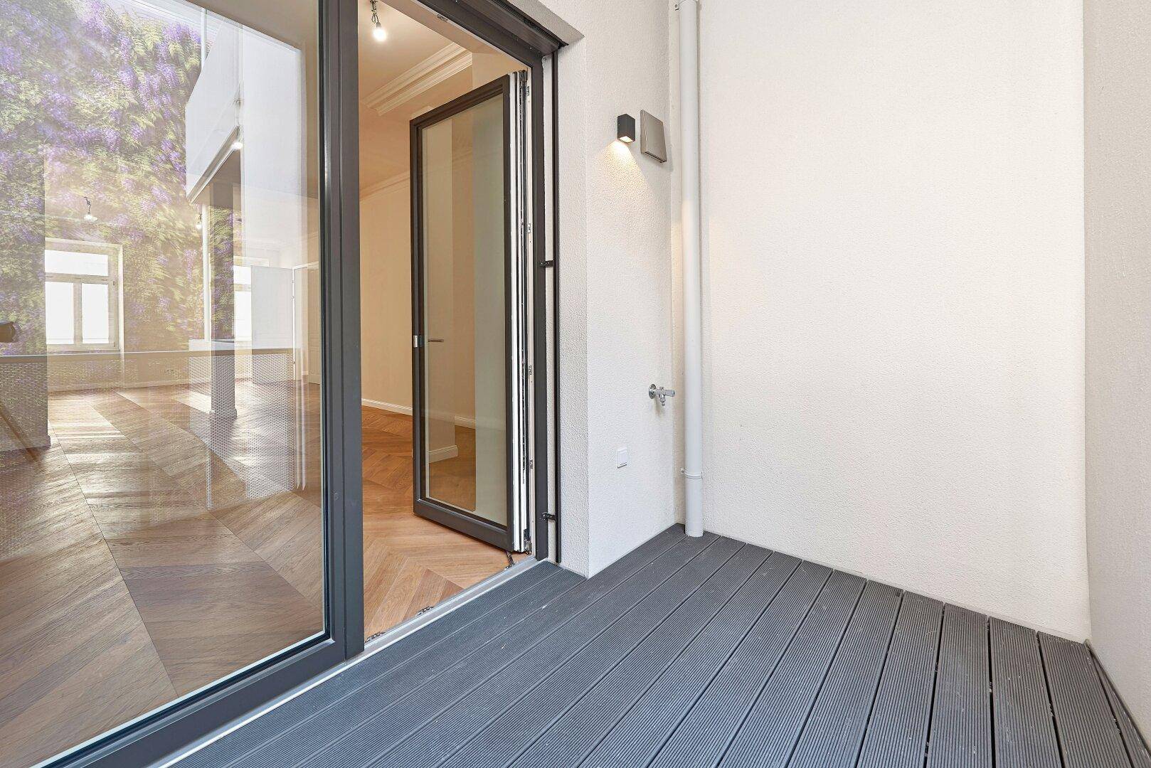 Heller Balkon mit Holzboden und Zugang zum Innenraum, ideal für entspannte Stunden.