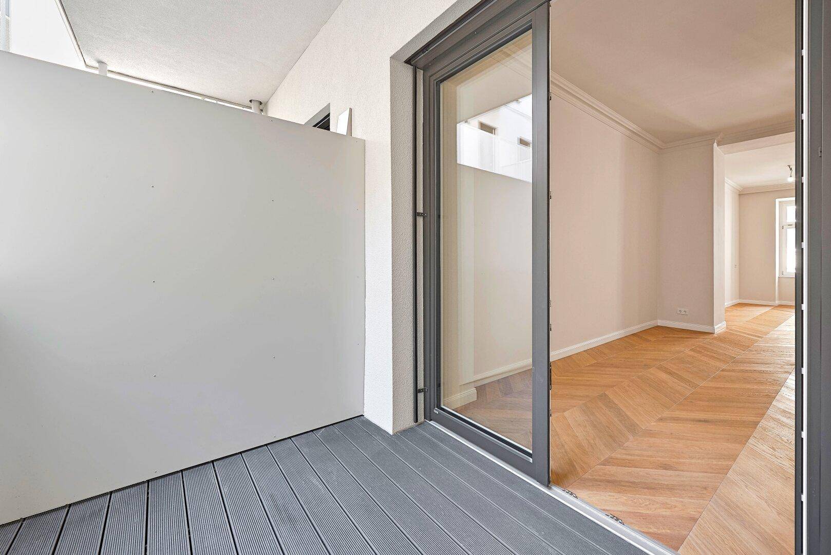 Geräumiger Balkon mit Holzboden und Blick auf den Innenhof, bietet Privatsphäre.