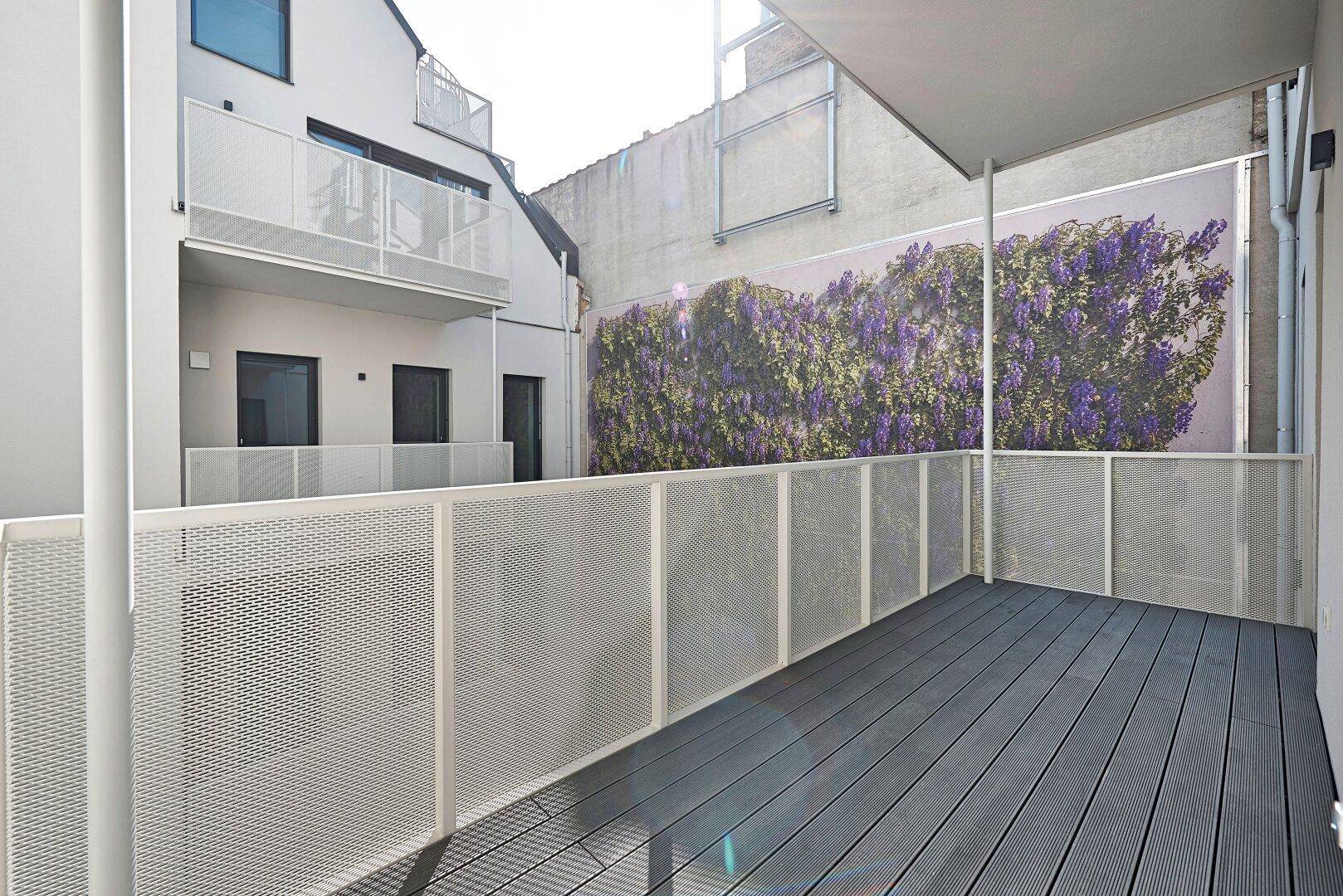 Geräumige Terrasse mit modernem Bodenbelag und einer dekorativen Wandbegrünung im Innenhof.