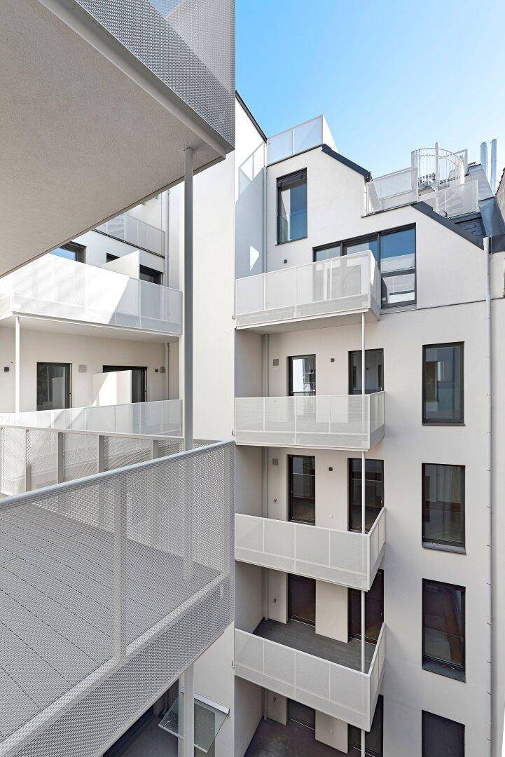Moderne Architektur mit weißen Fassaden und gestaffelten Balkonen in einem Innenhof.
