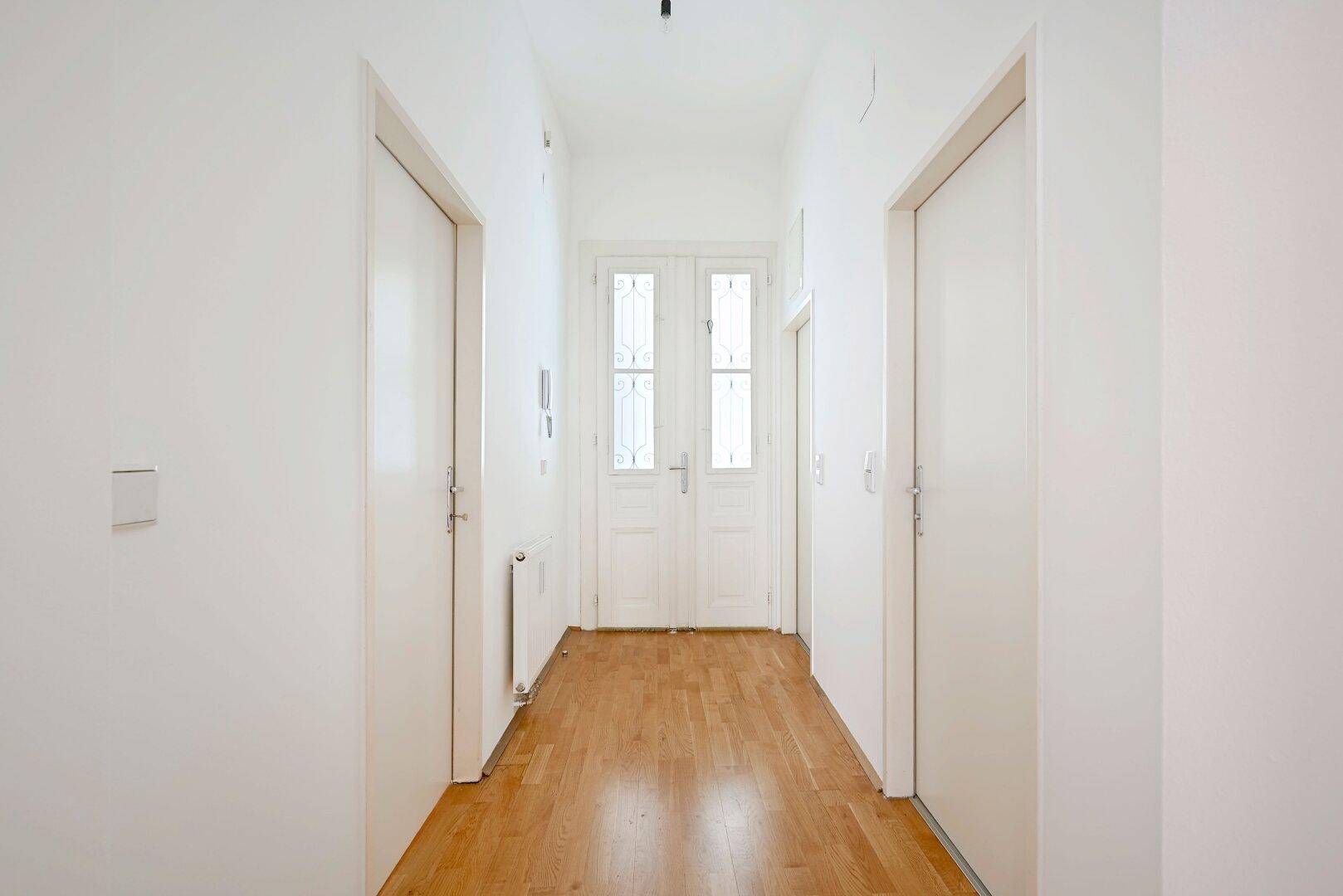 Heller Flur mit Parkettboden und dekorativen Doppeltüren am Ende, verbindet die Wohnbereiche.