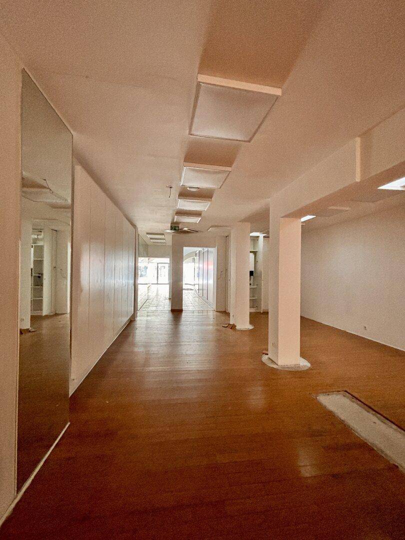Langer, heller Gewerberaum mit Holzboden, weißen Wänden und Spiegelfläche, bietet vielseitige Nutzungsmöglichkeiten.