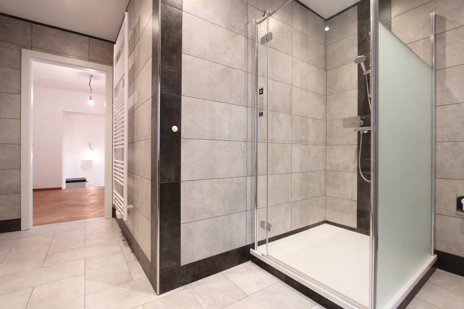Modernes Badezimmer mit begehbarer Dusche, großformatigen Fliesen und beheiztem Handtuchhalter.