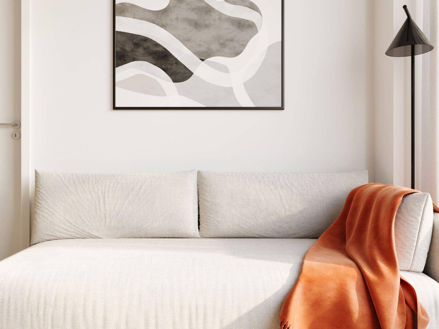 Modernes Sofa mit orangefarbener Decke und abstrakter Kunst an der hellen Wand.
