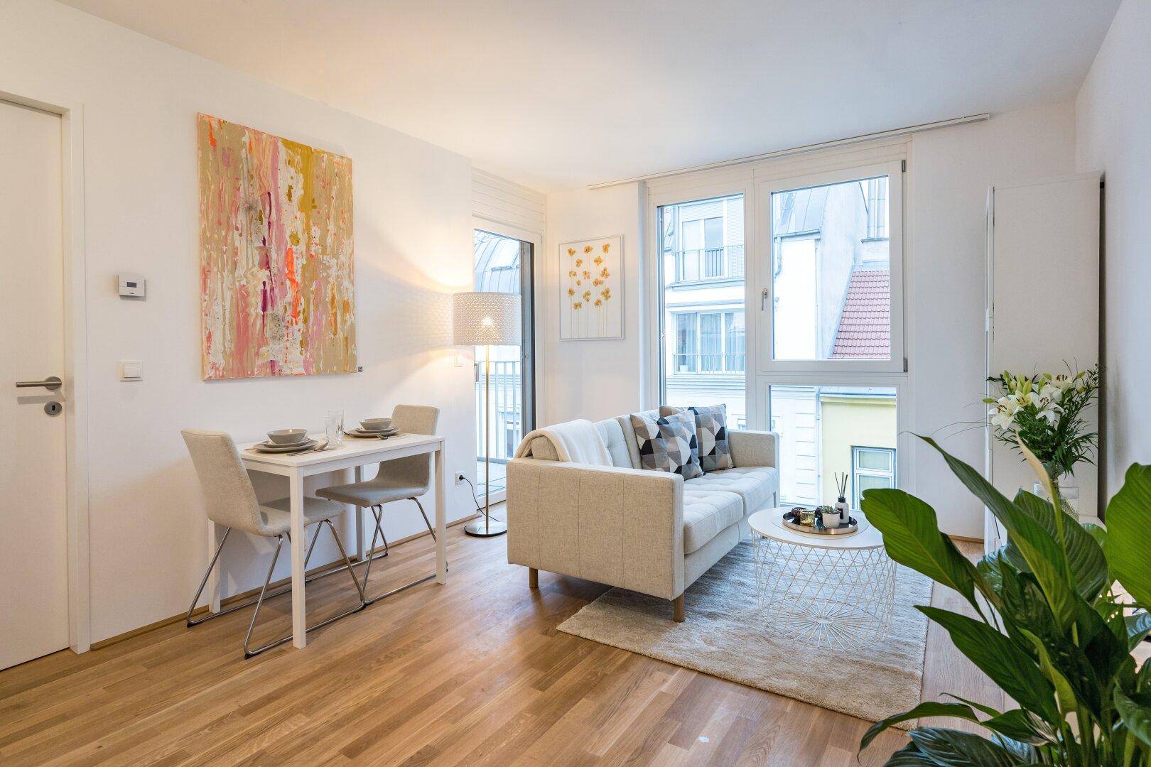 Heller Wohn- und Essbereich mit Holzboden, Sofa und Esstisch.