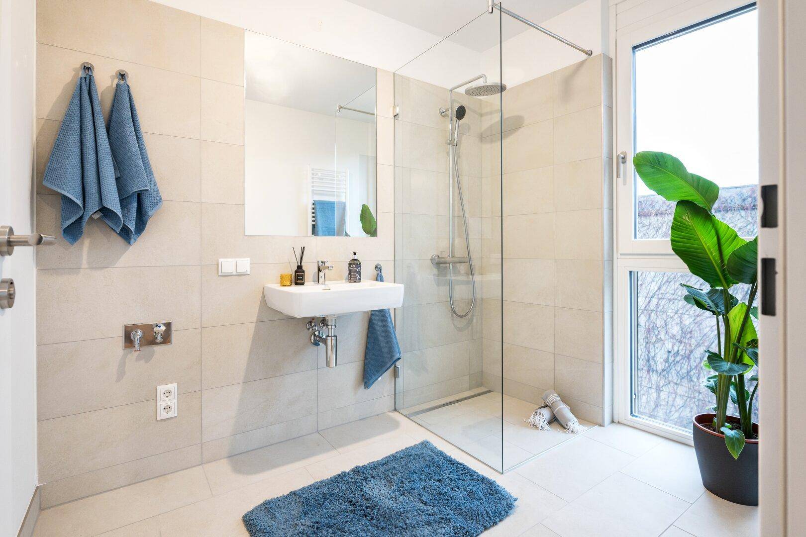Modernes Badezimmer mit begehbarer Dusche, großformatigen Fliesen und Fenster.