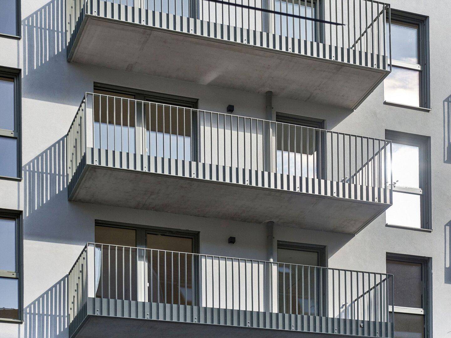 Nahaufnahme der modernen Balkone mit Metallgeländern an der Fassade des Wohngebäudes.