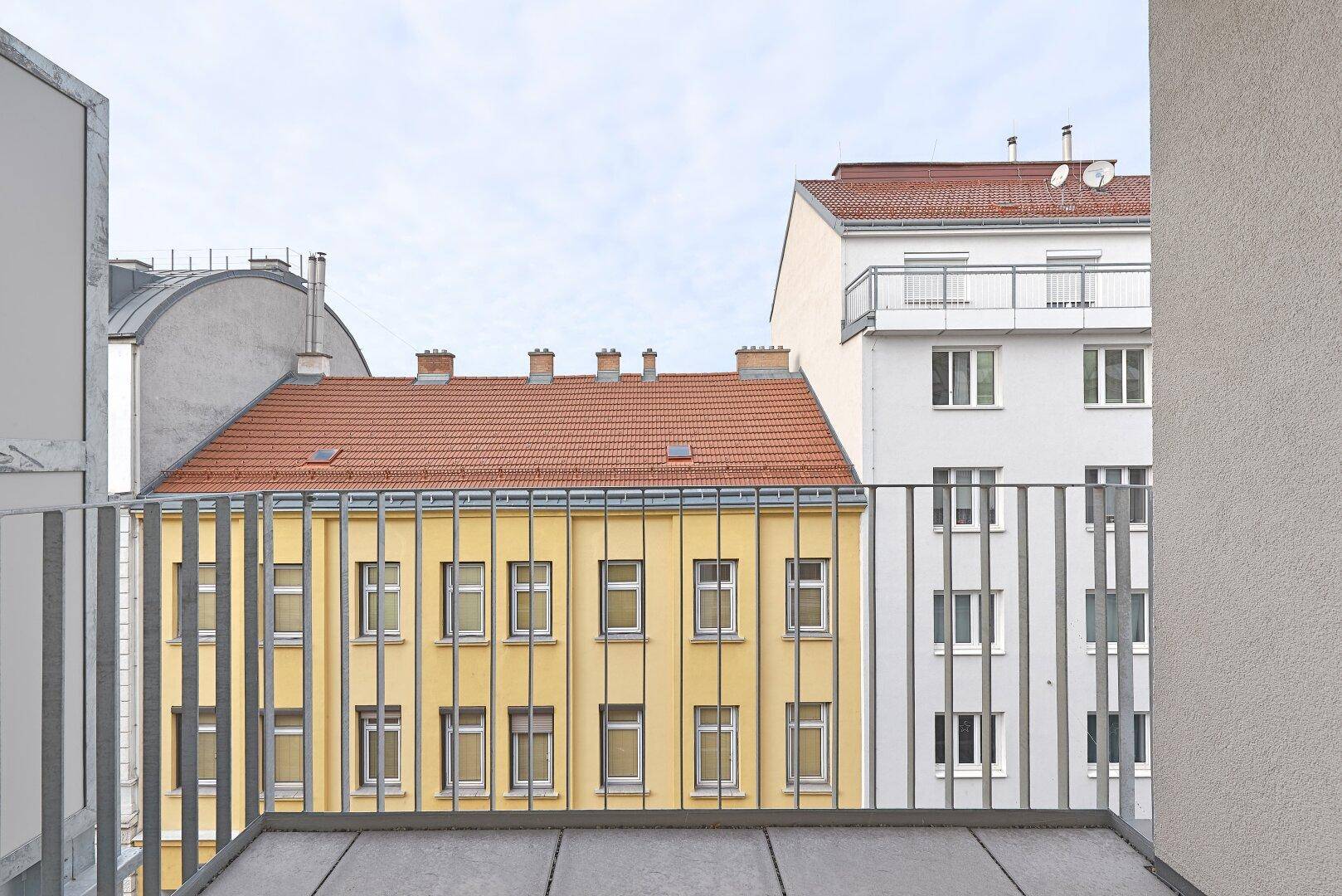 Blick vom Balkon auf die umliegenden Gebäude mit roten Dächern.