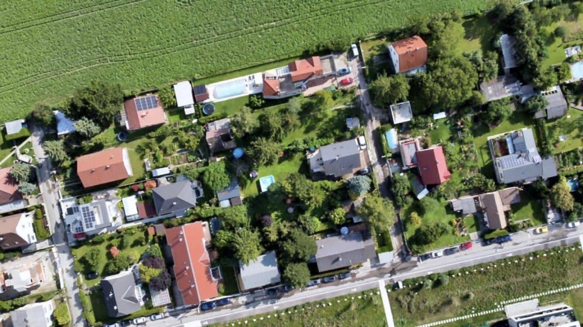 Luftaufnahme eines Wohngebiets mit Einfamilienhäusern, Gärten und angrenzenden Feldern.