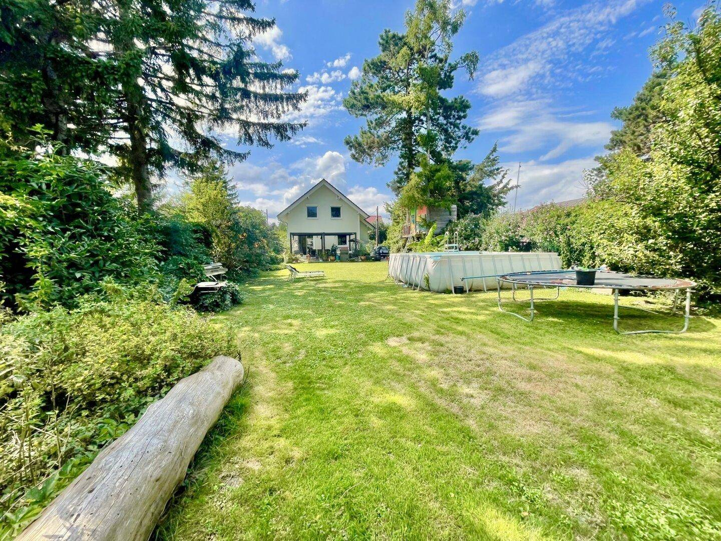 Großer Garten mit Rasenfläche, Aufstellpool und Trampolin, ideal für Familienaktivitäten.