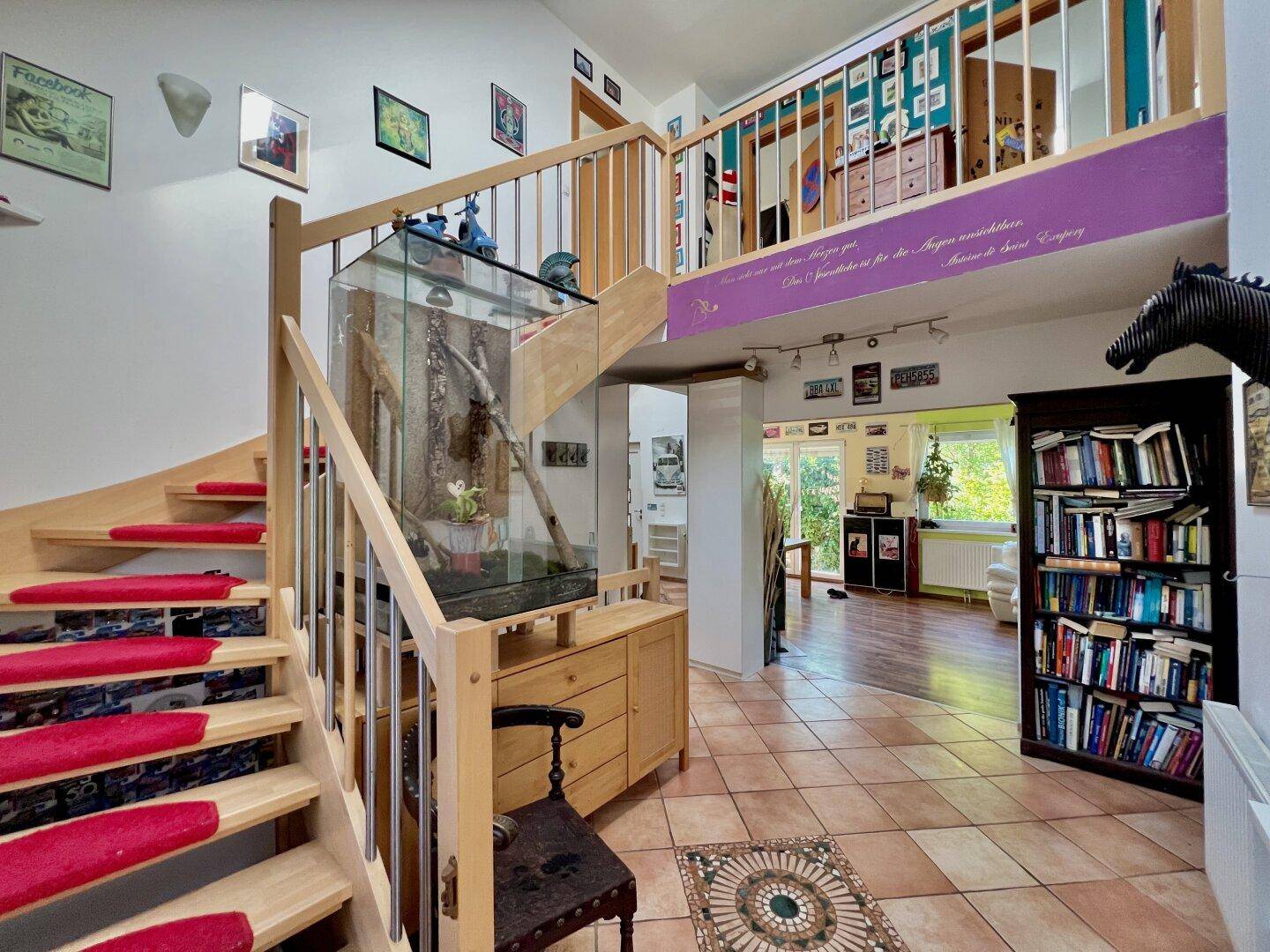 Geräumiger Eingangsbereich mit Holztreppe, Fliesenboden und offenem Galeriebereich.