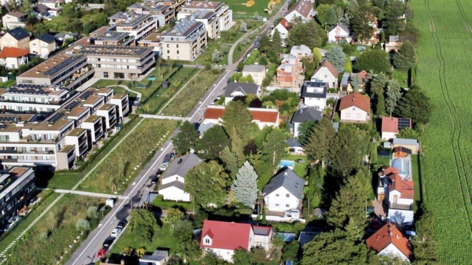 Luftaufnahme eines Wohngebiets mit einer Mischung aus neuen und älteren Häusern und viel Grün.