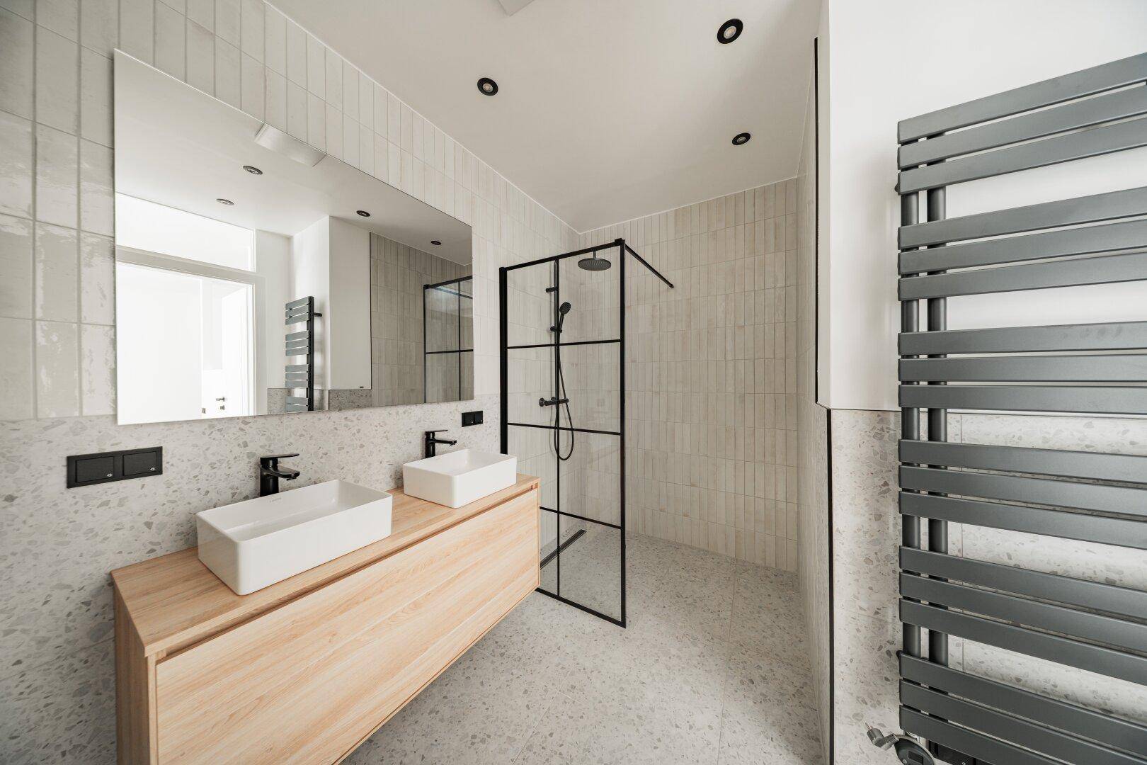 Modernes Badezimmer mit Doppelwaschbecken, begehbarer Dusche und Handtuchheizkörper.