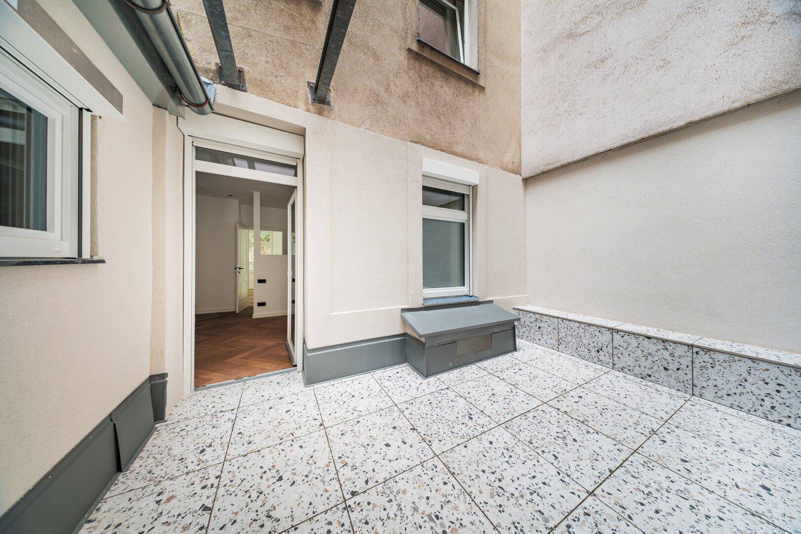 Kleine geflieste Terrasse im Innenhof mit Zugang zum Gebäude.