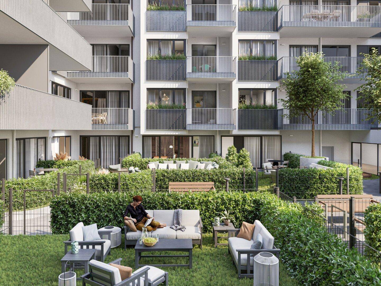 Gemeinschaftlicher Gartenbereich mit modernen Sitzgelegenheiten und gepflegten Hecken zwischen den Gebäuden.