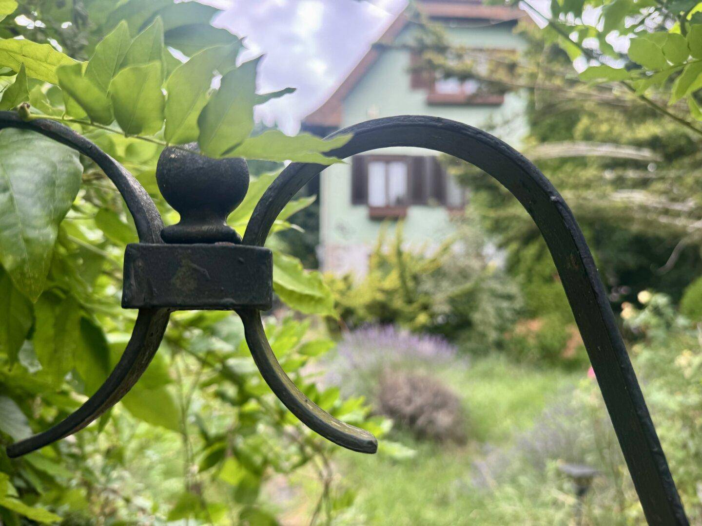 Detailaufnahme eines Gartenzauns mit unscharfem Blick auf das Haus im Hintergrund.