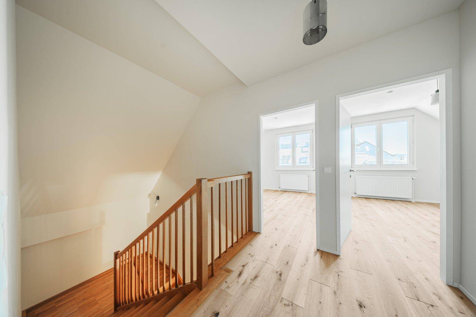 Heller Flur im Dachgeschoss mit Holztreppe und Zugang zu weiteren Zimmern.