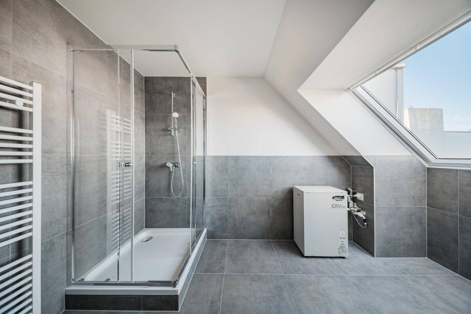 Geräumiges Badezimmer im Dachgeschoss mit großer Duschkabine und Dachfenster.