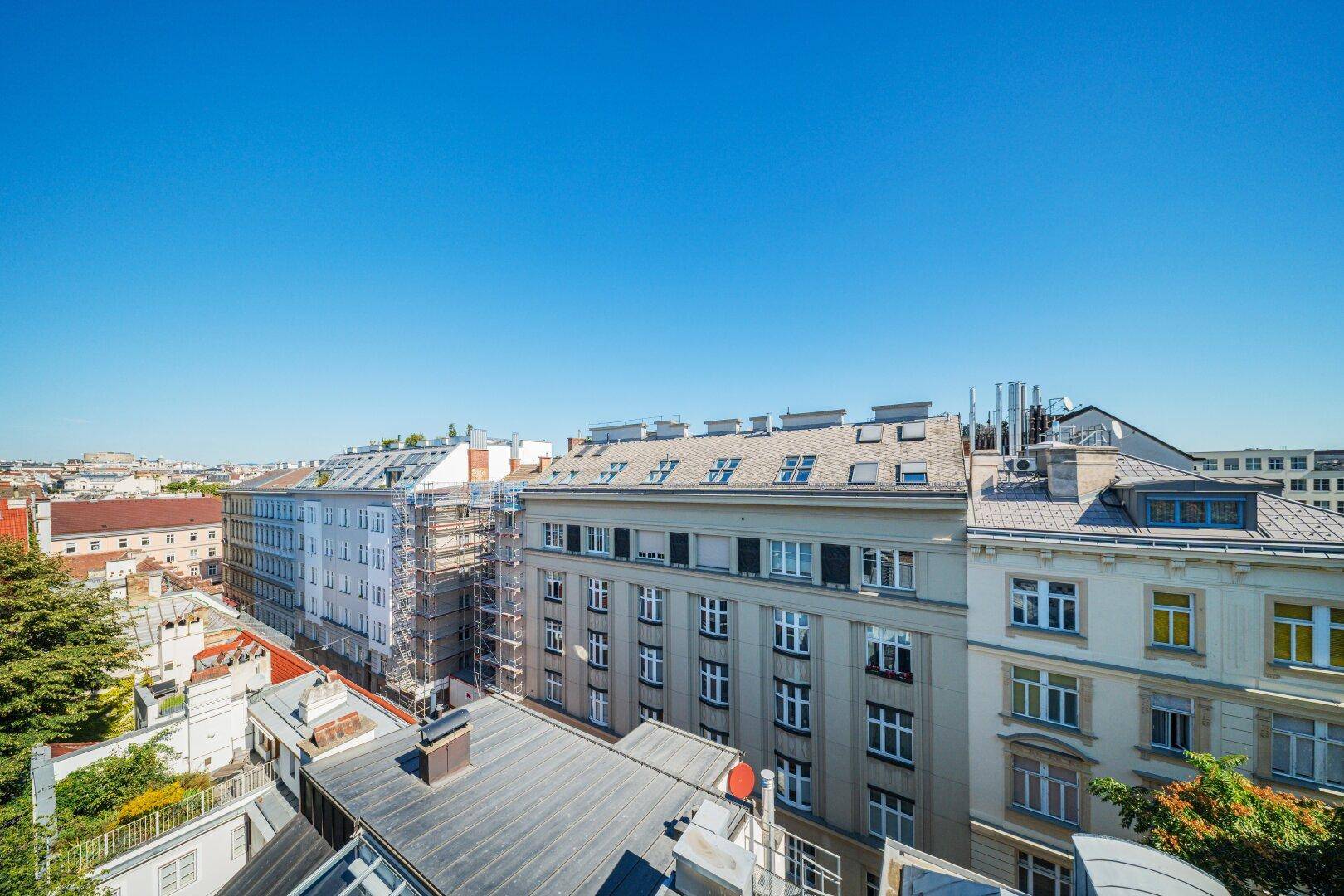Weitläufiger Blick über die Dächer der Stadt mit vielen Gebäuden und klarem Himmel.