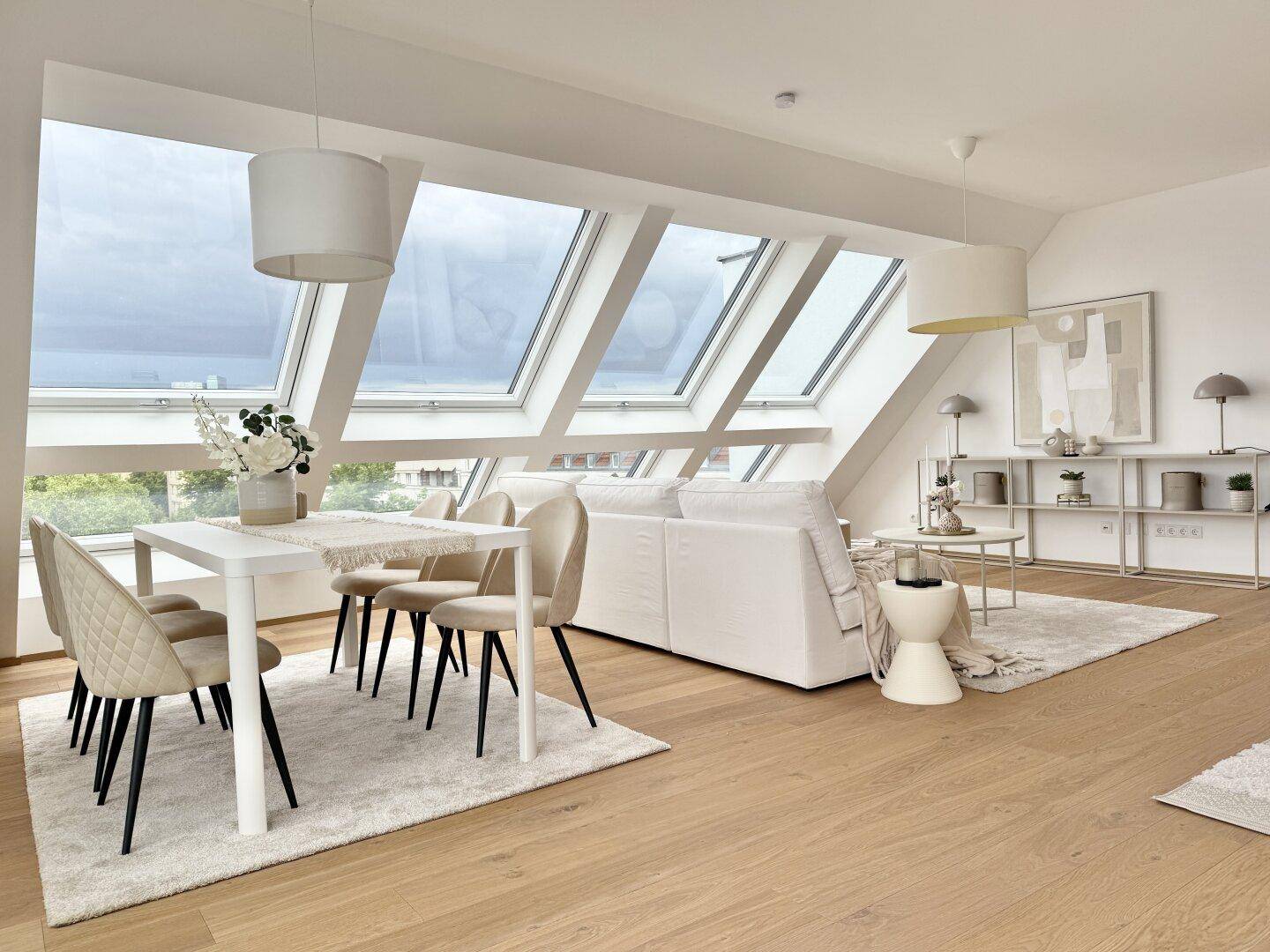 Heller Wohn- und Essbereich mit Dachschrägen, großen Dachfenstern und modernem Interieur.