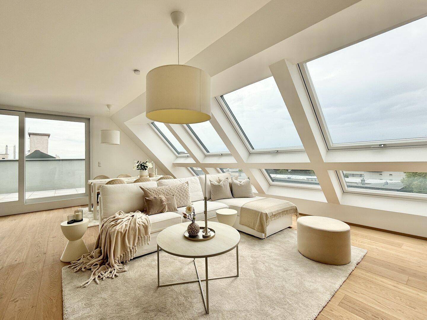 Heller Wohnbereich mit Zugang zu einem Balkon oder einer Terrasse und großen Dachfenstern.