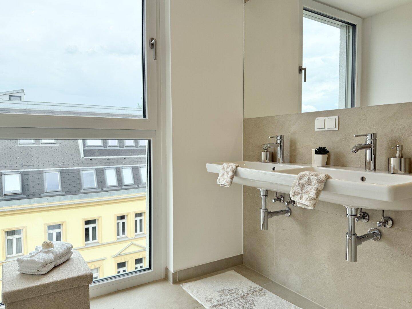 Doppelwaschbecken im modernen Badezimmer mit großem Fenster und Blick nach draußen.