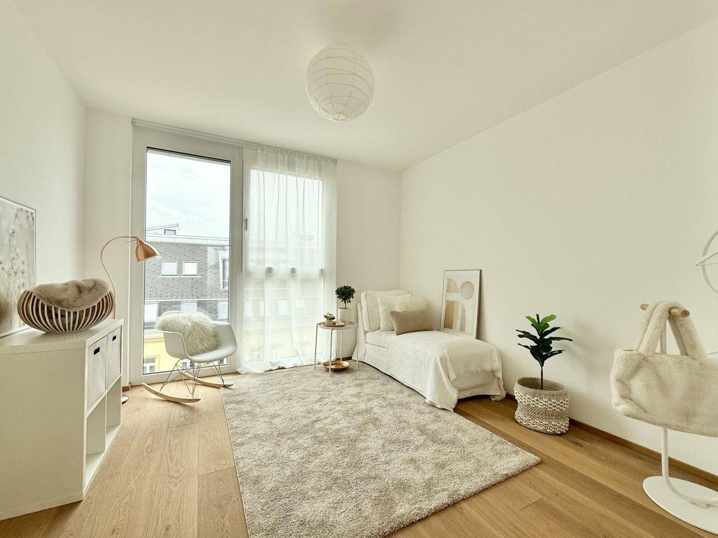 Freundliches Zimmer mit großem Fenster, Holzboden und heller, minimalistischer Einrichtung.
