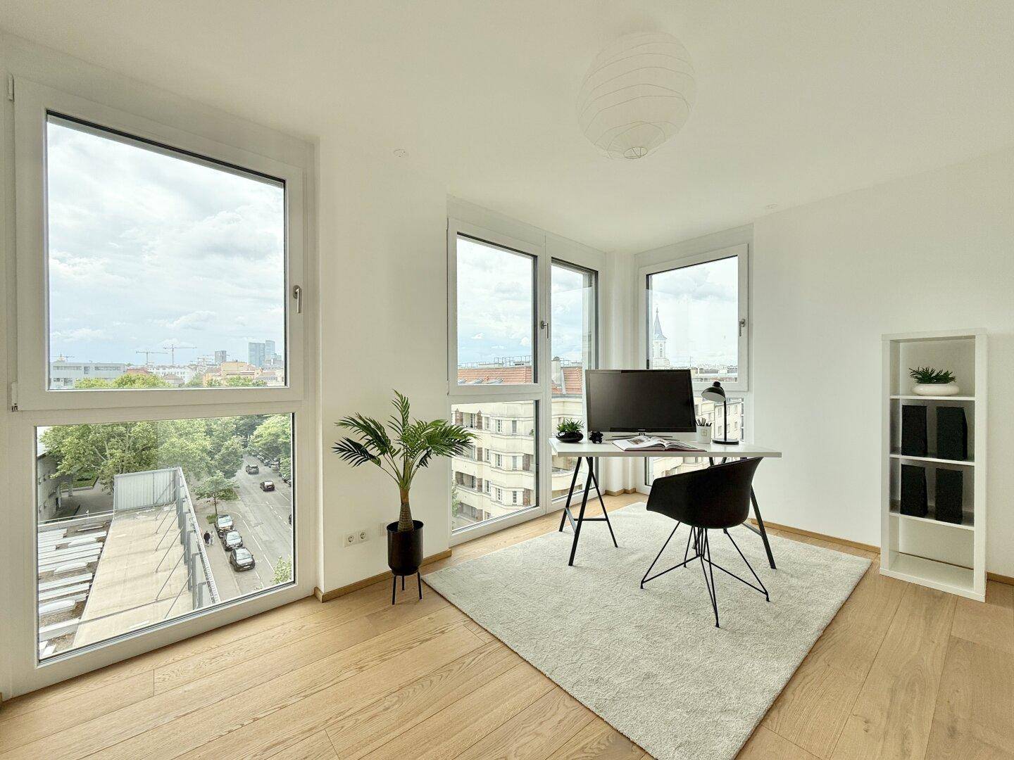 Helles Arbeitszimmer mit großen Fenstern, Stadtblick und modernem Schreibtisch.
