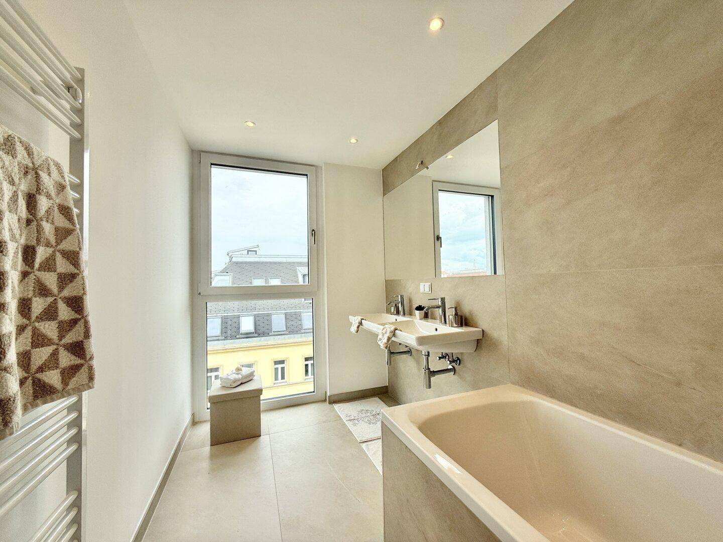 Modernes Badezimmer mit Badewanne, Doppelwaschbecken und großem Fenster.