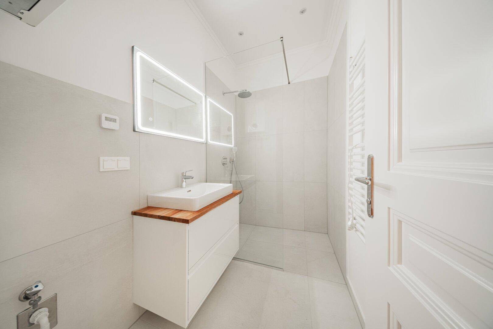 Modernes Badezimmer mit begehbarer Dusche, Einzelwaschbecken und beheiztem Handtuchhalter.