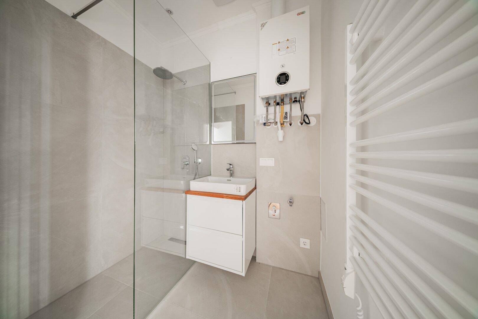 Modernes Badezimmer mit ebenerdiger Dusche, Einzelwaschbecken und Handtuchheizkörper.