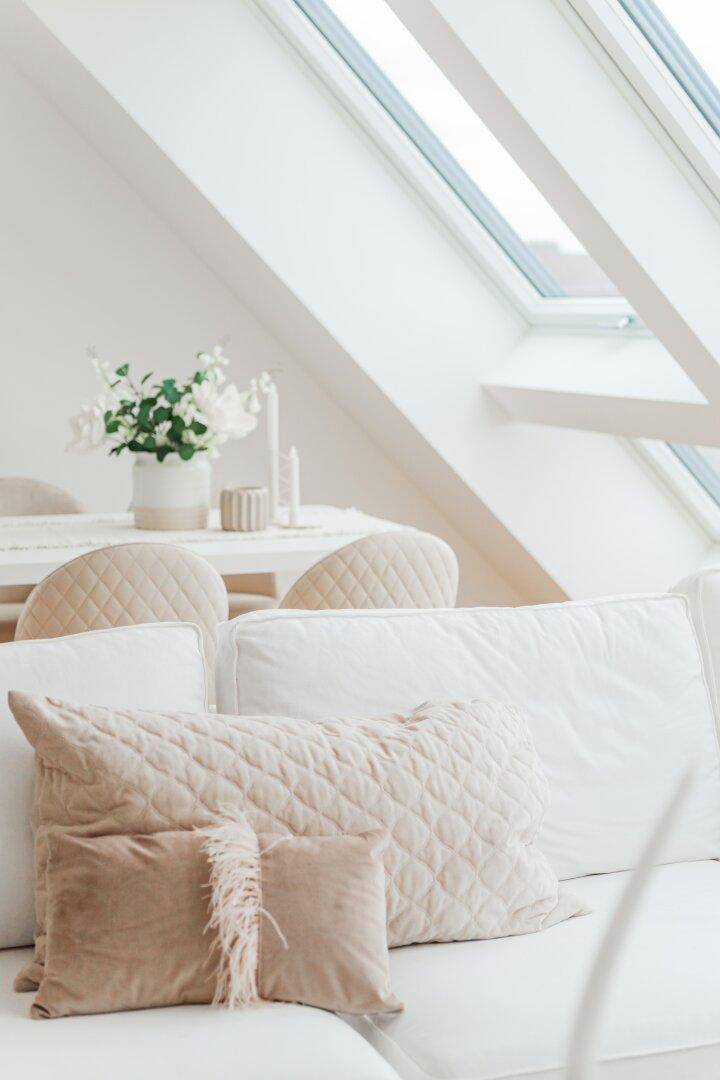 Nahaufnahme von Kissen auf einem Sofa mit Blick auf die Dachfenster und den Essbereich.