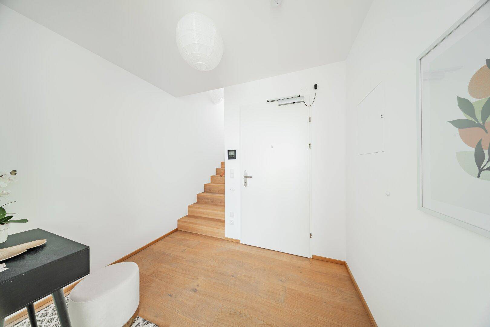 Heller Eingangsbereich mit Holzboden und Treppe zum oberen Stockwerk.